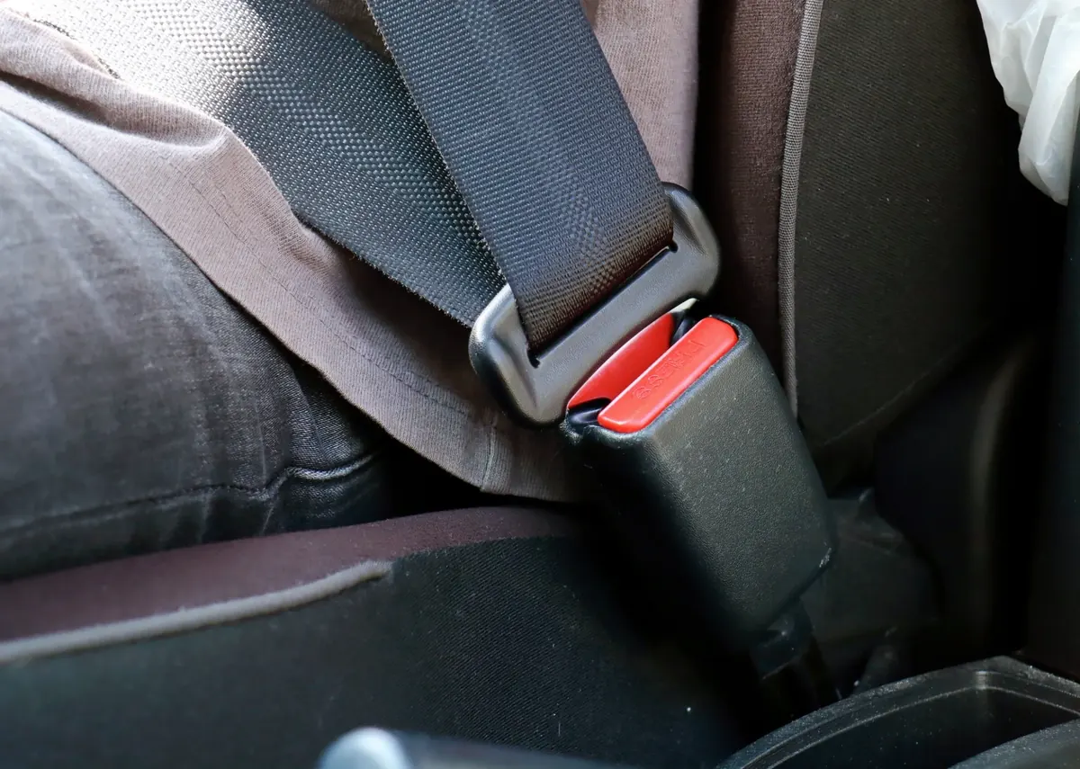 A seatbelt fastened into its buckle on a vehicle seat, viewed close up