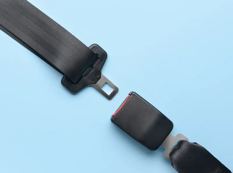 A seatbelt tongue and a seatbelt extender shown separated on a plain light blue background